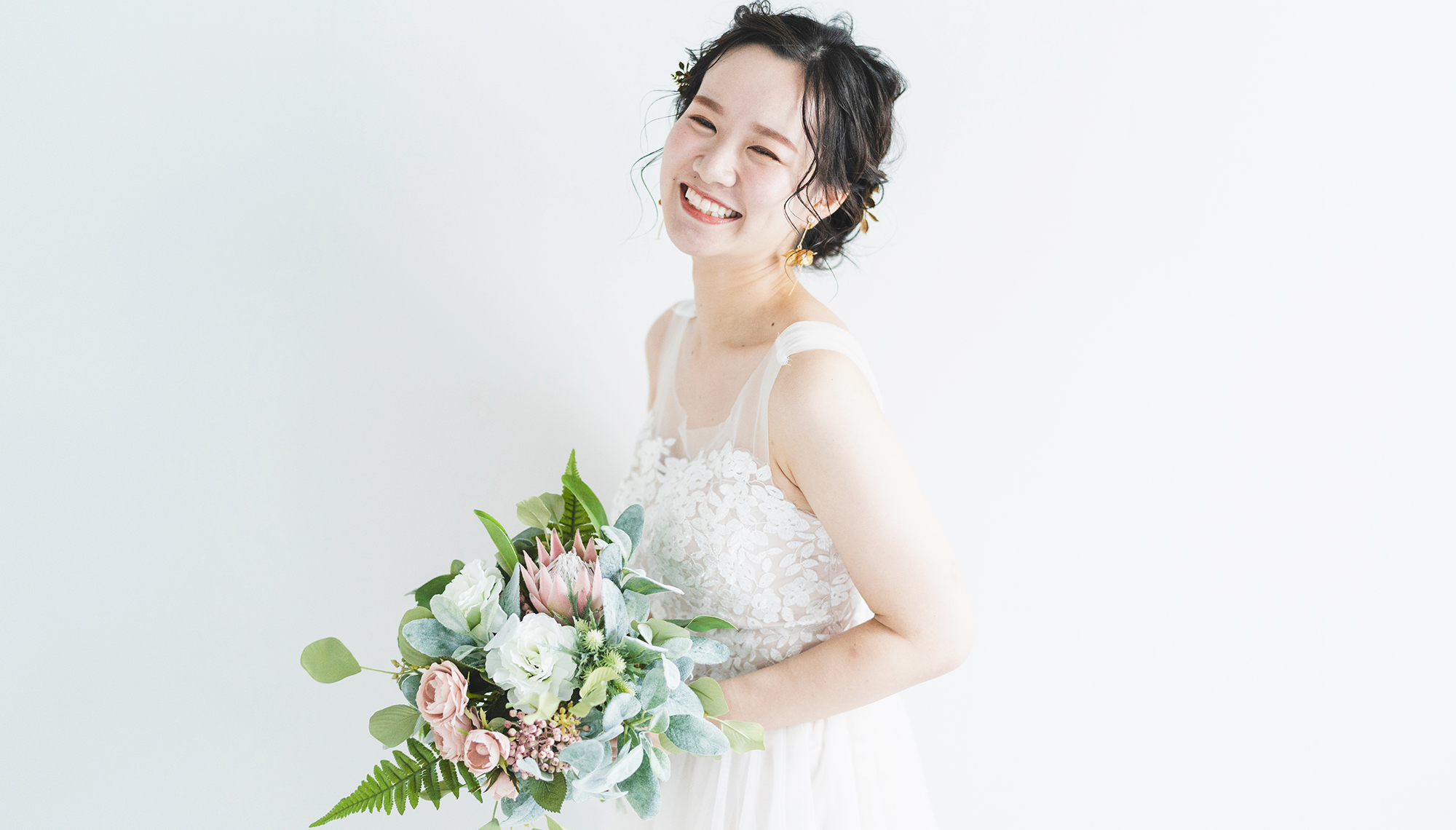白壁の前にウェディングドレス姿の女性が笑顔でこちらを見ている写真